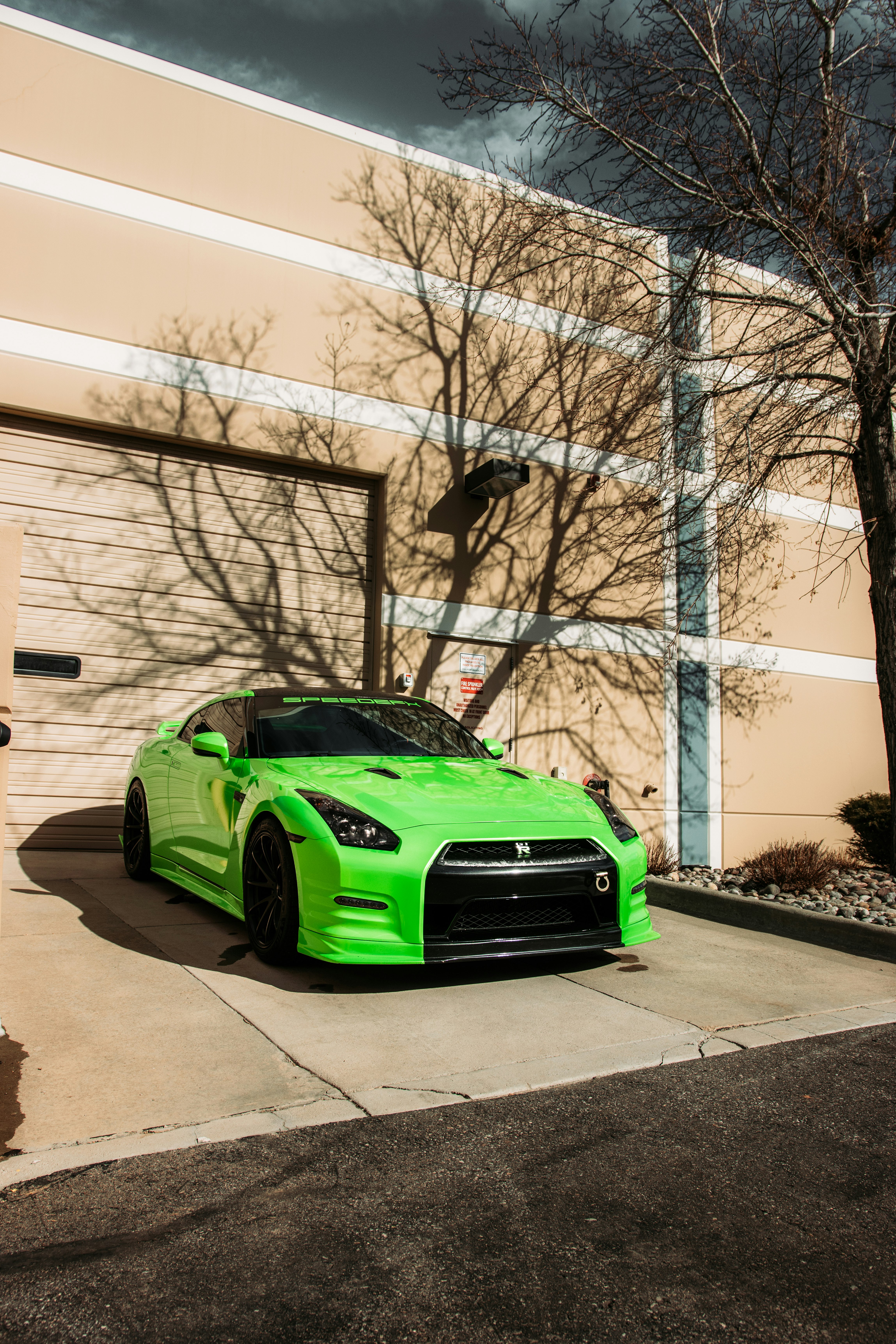 green car parked beside white building